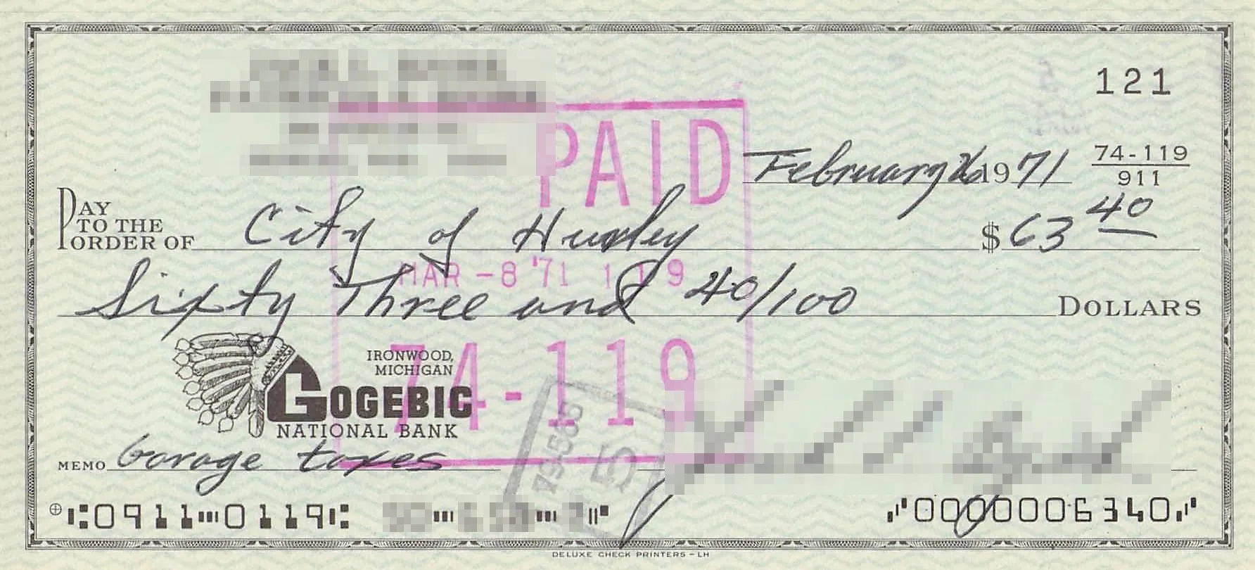 米国の小切手。PAID のスタンプが押され、中ほどに金額 63.40ドル、左下に銀行のロゴ、下端に E-13B の MICR ラインが印字されている